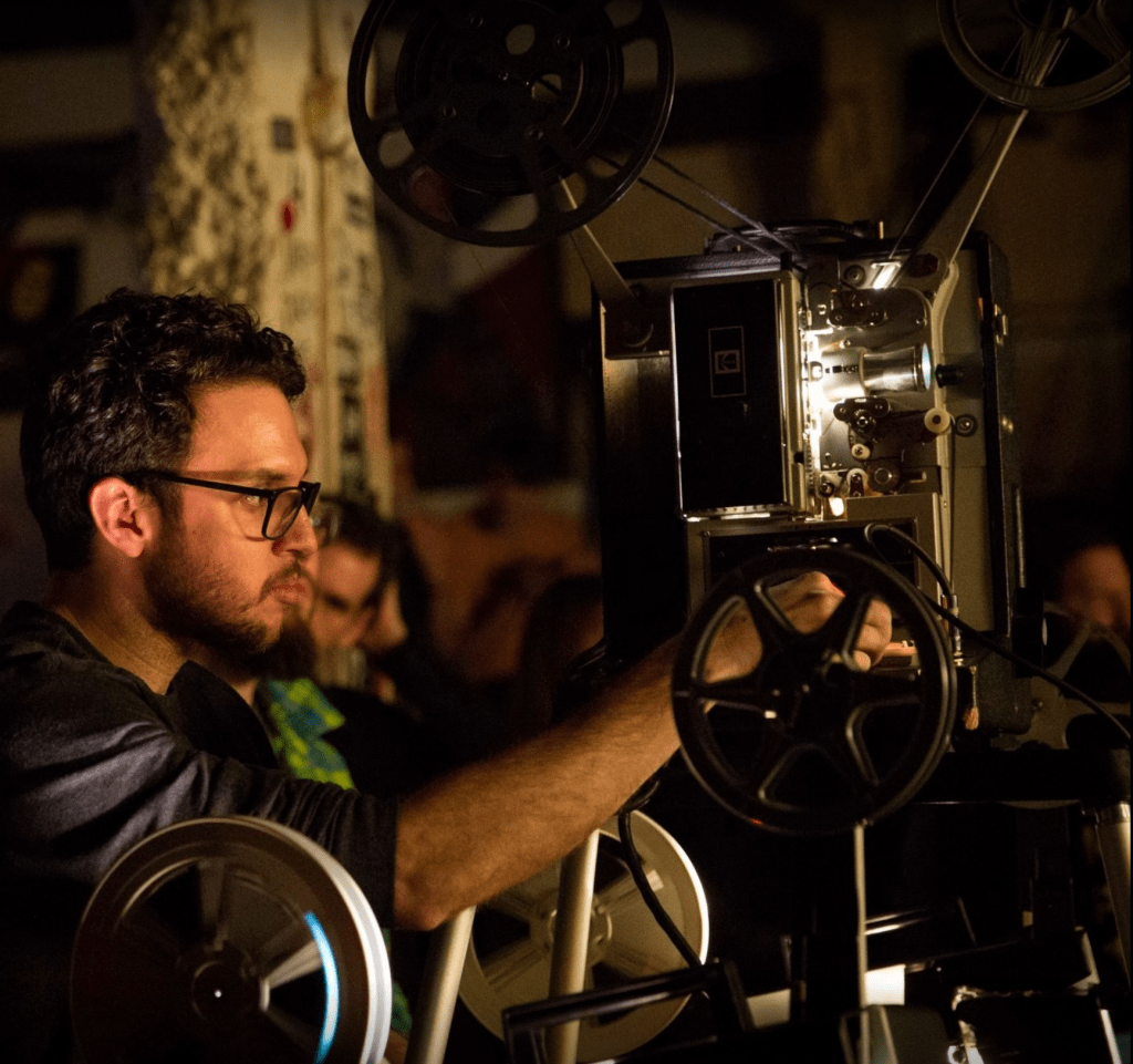 Dave Rodriguez standing at a 16mm film projector