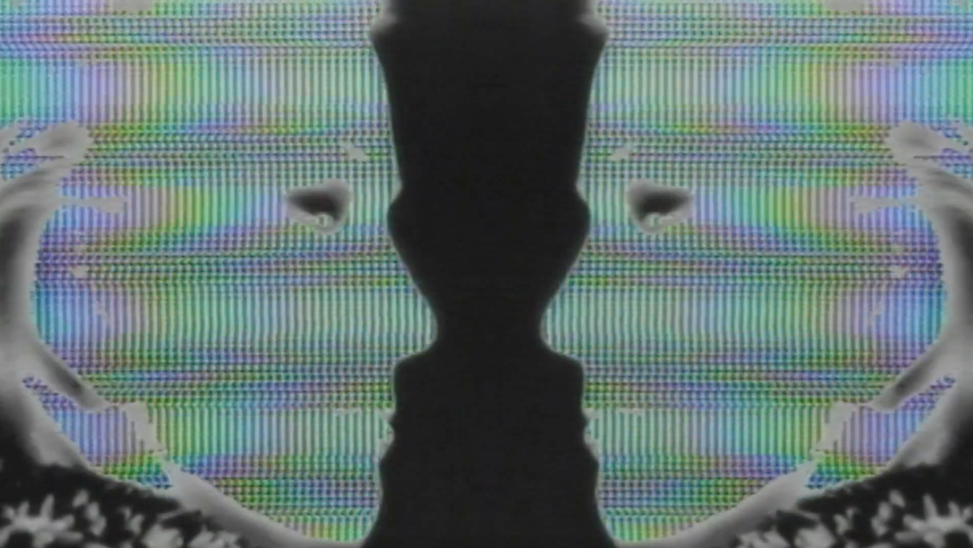 A still from the Faces music video of a mirrored woman's face looking at the center of the frame
