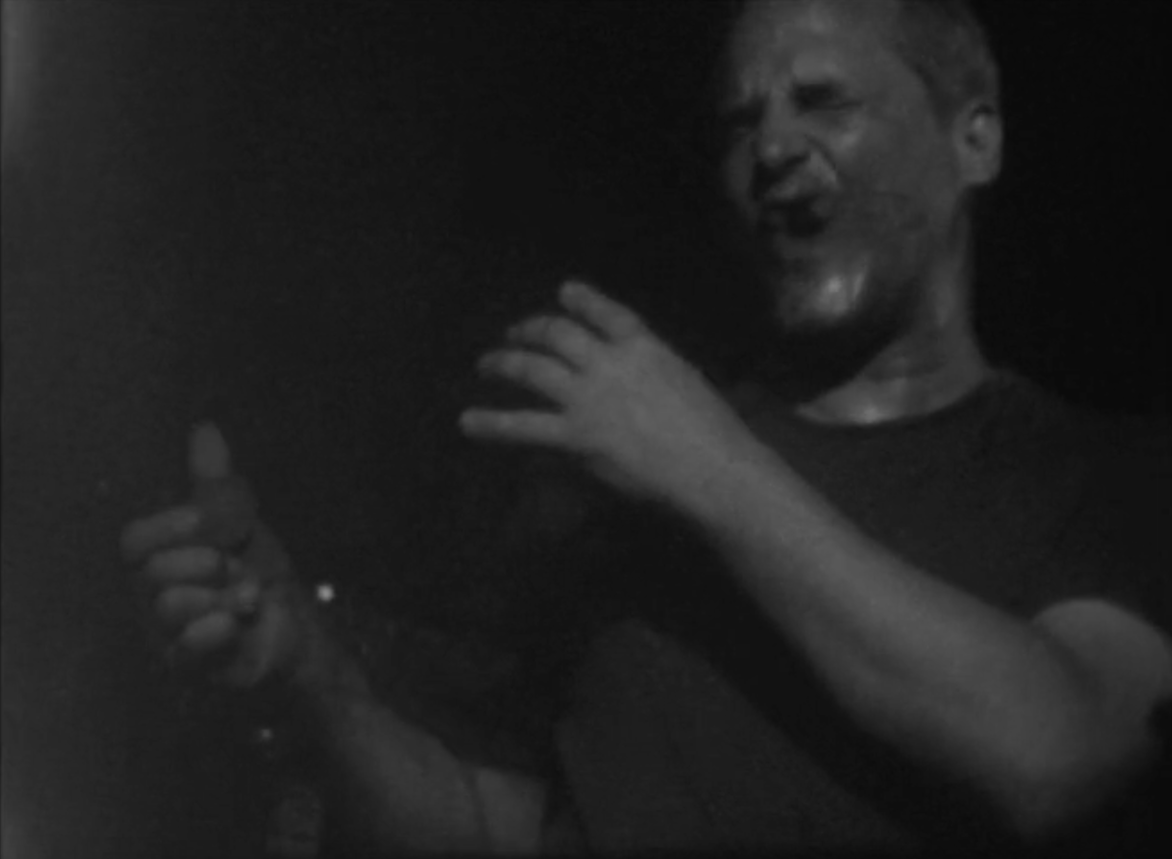 8mm film image of Justice Yeldham performing with a large shard of glass attached to a contact microphone